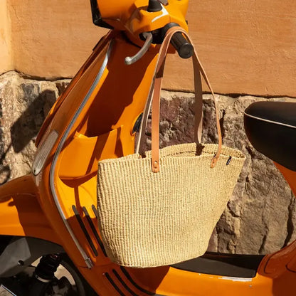 Woven bag on an orange scooter against a stone wall