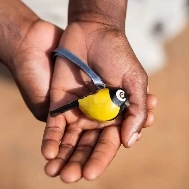 Hand holding a small yellow and black bird ornament