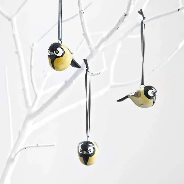 Decorative bird ornaments hanging from branches on a white background