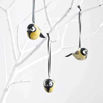 Decorative bird ornaments hanging from branches on a white background