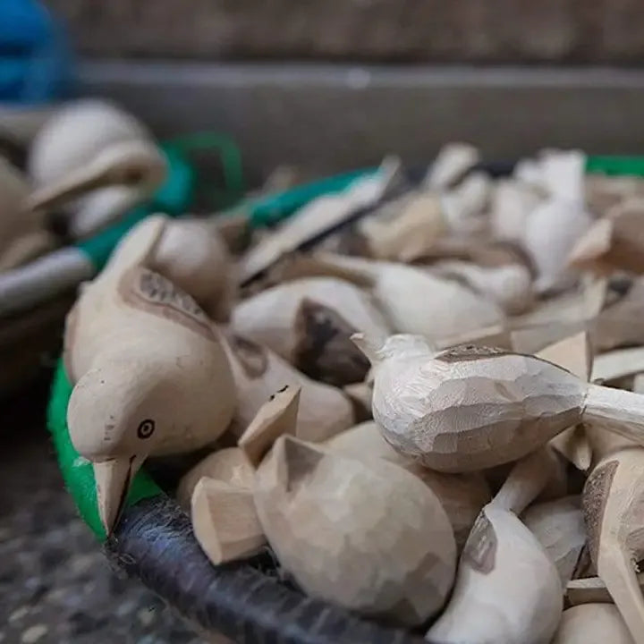 Wooden bird figurines on a textured surface with blurred background