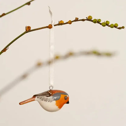 Decorative bird ornament hanging from a branch against a light background