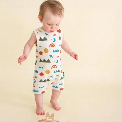Baby wearing a colorful patterned romper on a beige background