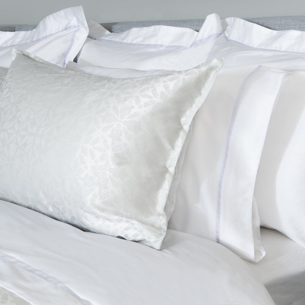 White satin pillowcases on a bed with a neutral background
