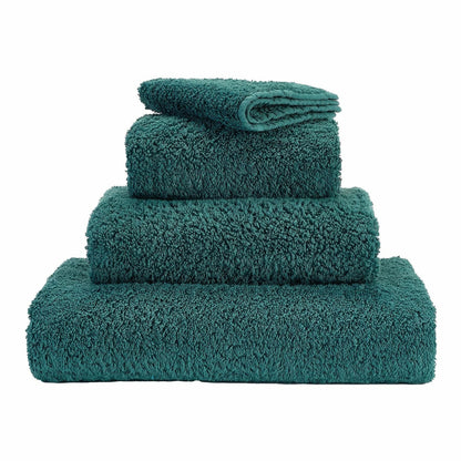 A set of dark green towels neatly stacked on top of each other.