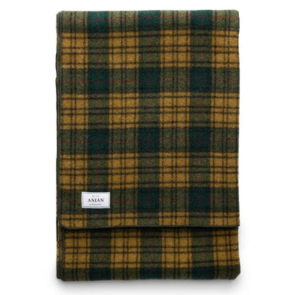 A folded plaid blanket in a mustard yellow and dark green tartan pattern, featuring a small white brand label that reads 'ANiÁN'.