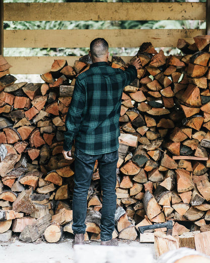 Man wearing a men's plaid flannel shirt while stacking firewood in a rustic setting unisex in Kelowna