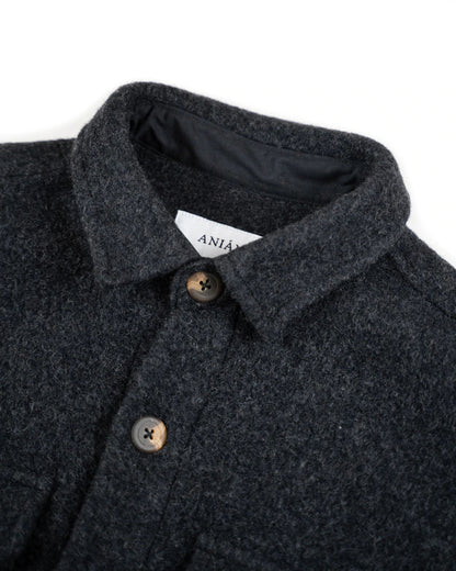 Close-up of a dark charcoal gray textured wool coat with a pointed collar, brown buttons, and a white brand label reading 'ANIAN' on a white background.