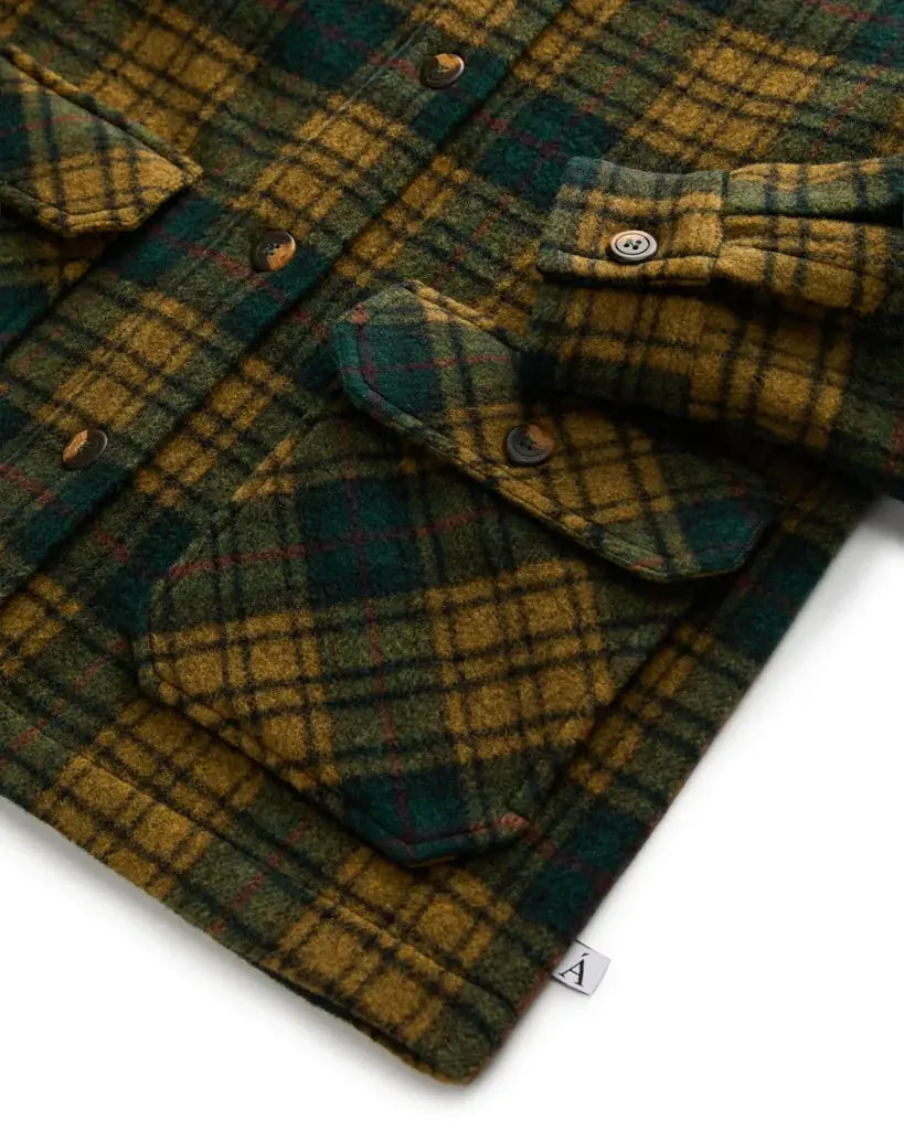 Close-up of a green and brown plaid shirt with buttons on a white background