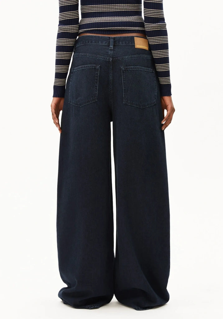 A model shown from the back wearing dark navy wide-leg denim jeans and a navy striped long-sleeve crop top, photographed against a clean white background.