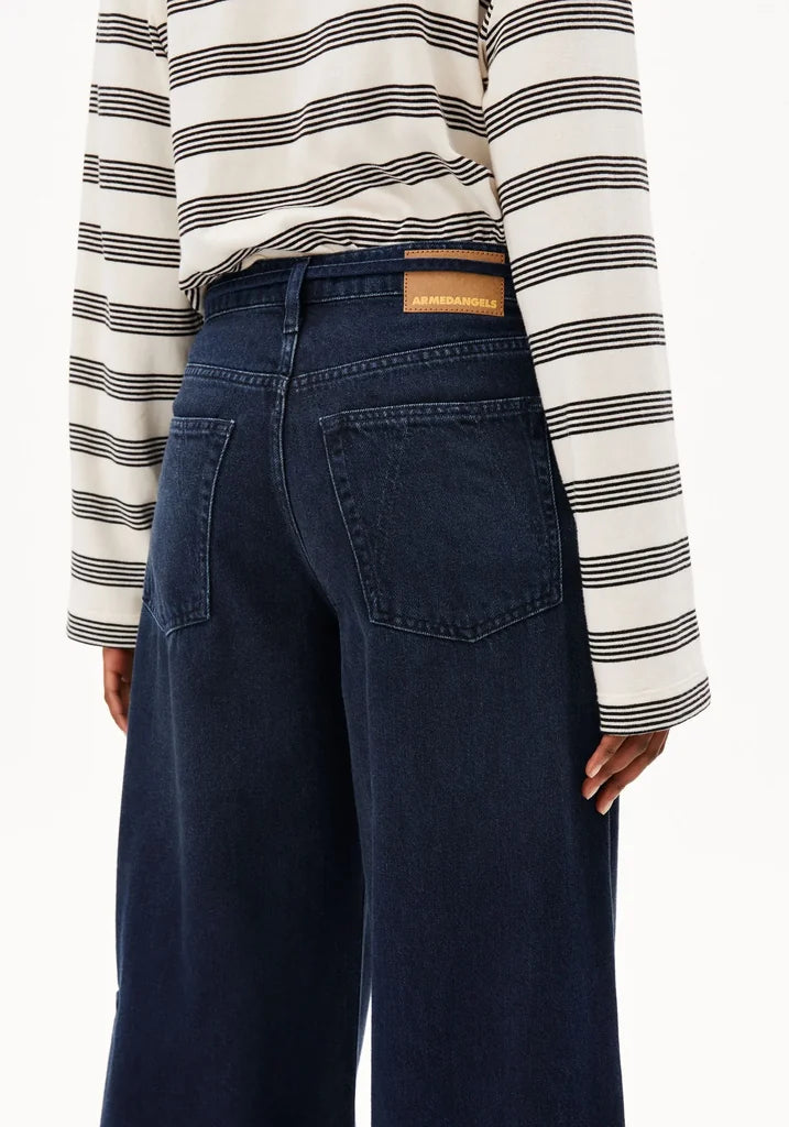 Person wearing a striped shirt and dark blue jeans with a visible brand patch.