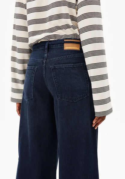 Person wearing a striped shirt and dark blue jeans with a visible brand patch.