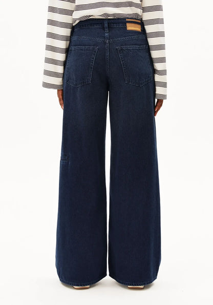 Back view of a person wearing dark blue wide-leg denim jeans and a cream and navy striped long-sleeve top, shown against a plain white background.