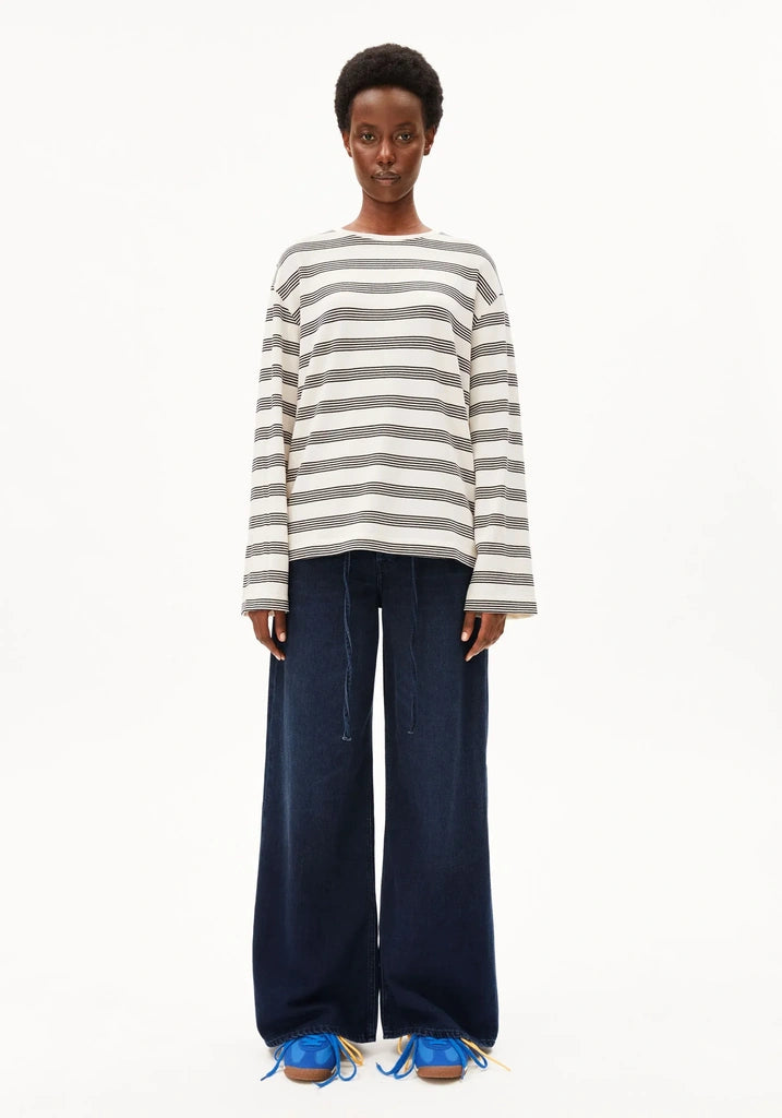 Person wearing a striped sweater and wide-leg jeans on a white background