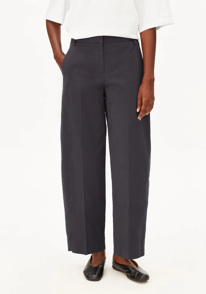 A model wearing dark charcoal gray wide-leg cropped trousers, styled with a white short-sleeve top and black flats, against a plain white background.