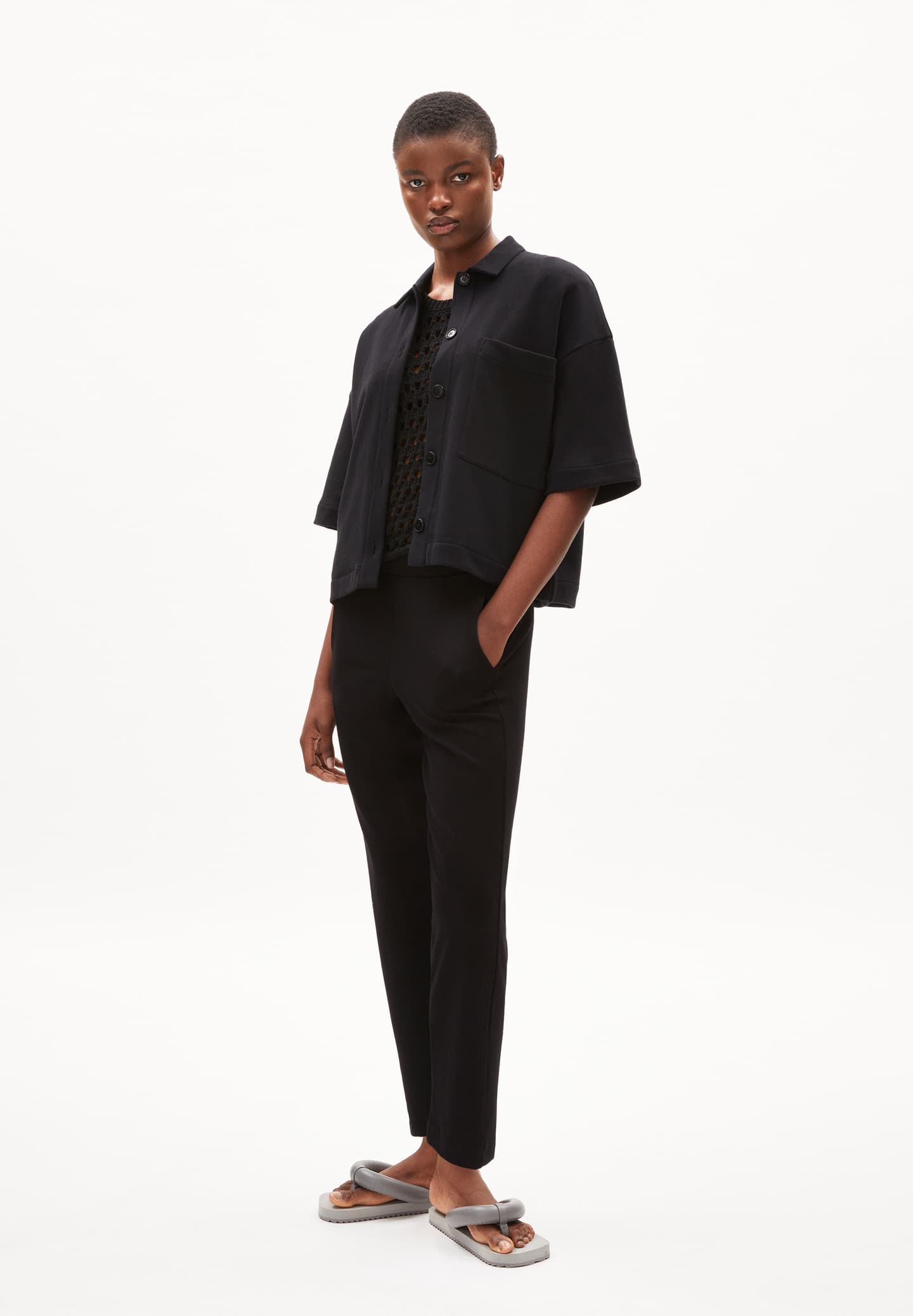 ARMEDANGELS Canada  black tapered pants styled with a loose black shirt and gray sandals in Kelowna