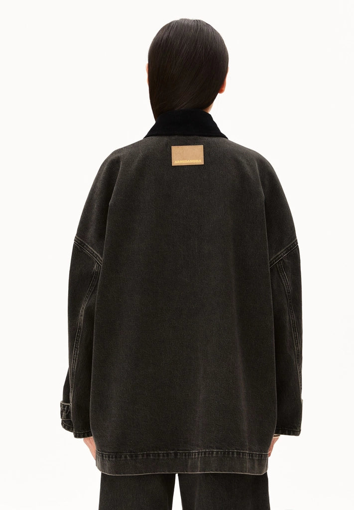 Back view of a woman wearing ARMEDANGELS Canada Denim Jacket Cord Collar, showing the oversized fit and label patch, against a white background.