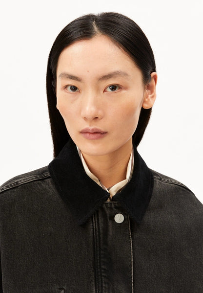 Close-up of a woman wearing ARMEDANGELS Canada Denim Jacket Cord Collar, showing the corduroy collar and metal buttons, against a white background.