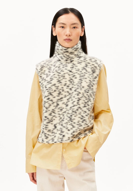 Woman wearing ARMEDANGELS Canada Dotted Mohair-Blend Knit Vest in Oatmilk-Black over a pale yellow shirt with cream trousers, front view against a white background.