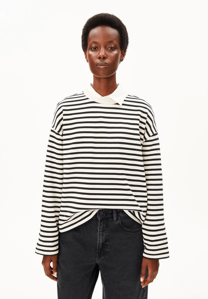 Woman wearing ARMEDANGELS Canada Frankaa Maarlen Stripe Sweatshirt in Undyed-Black over a white collared shirt with black jeans, front view against a white background.