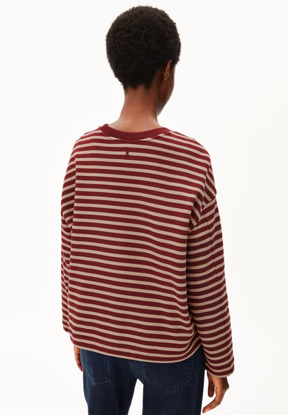 Back view of a woman wearing ARMEDANGELS Canada Frankaa Maarlen Stripe Sweatshirt in Velvet Red-Honey Reed with dark jeans, against a white background.