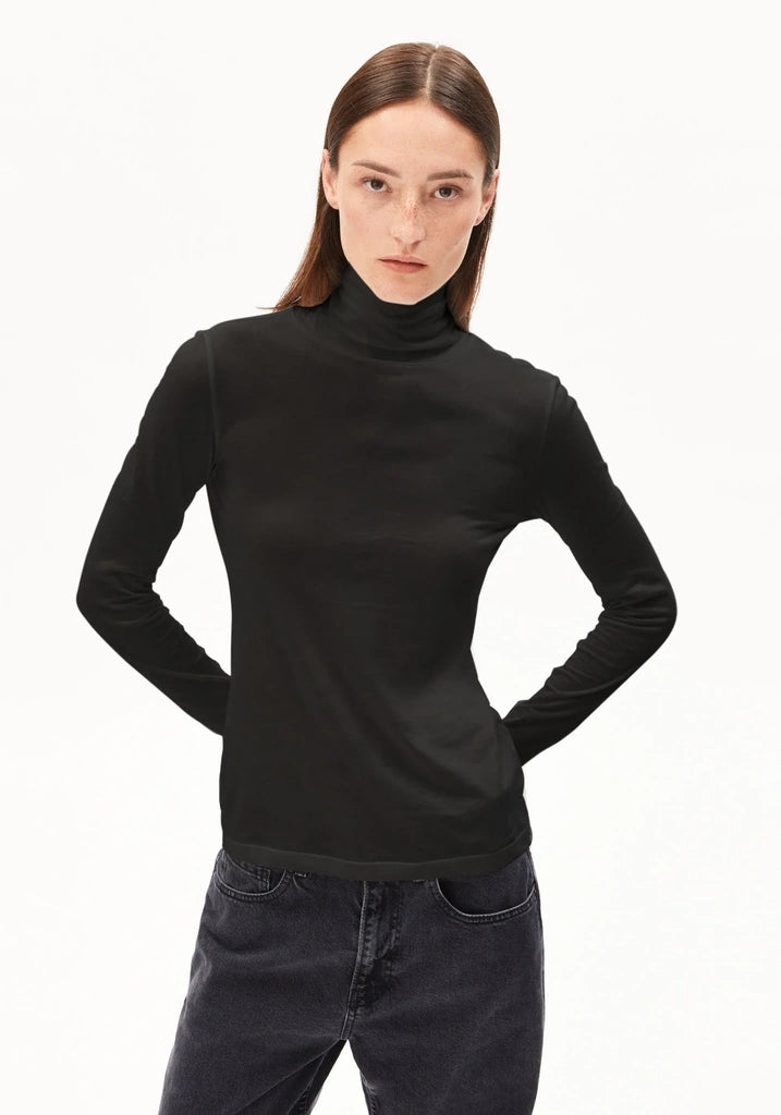 Woman wearing a black turtleneck sweater and dark jeans on a white background
