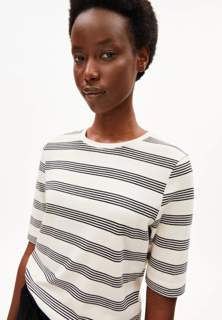 Close-up of a woman wearing ARMEDANGELS Canada Jaanisara Fine Stripe T-Shirt in Oatmilk-Black, showing the round neck and stripes, against a white background.
