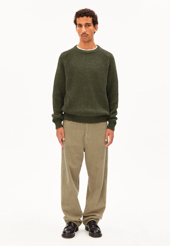 Full-length view of a man in the ARMEDANGELS Canada Kiaano Tweed Knit Sweater in Dark Earth Tweed, wearing beige cords and black shoes on a white background.