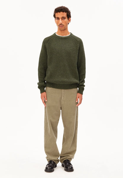 Full-length view of a man in the ARMEDANGELS Canada Kiaano Tweed Knit Sweater in Dark Earth Tweed, wearing beige cords and black shoes on a white background.