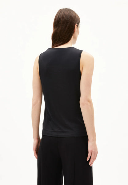Back view of a woman wearing the ARMEDANGELS Canada Laminiaa Sleeveless Top in black with black trousers on a white background.