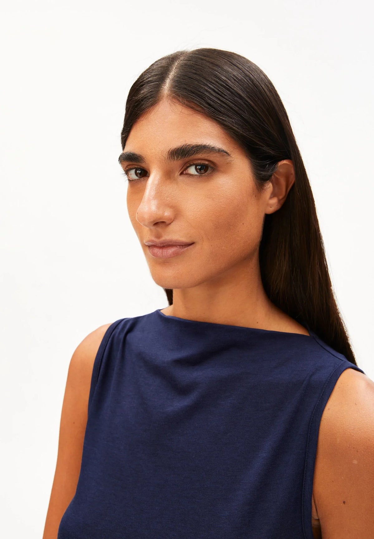 Close-up of the boat neckline on the ARMEDANGELS Canada Laminiaa Sleeveless Top in tinted navy, worn by a woman against a white background.