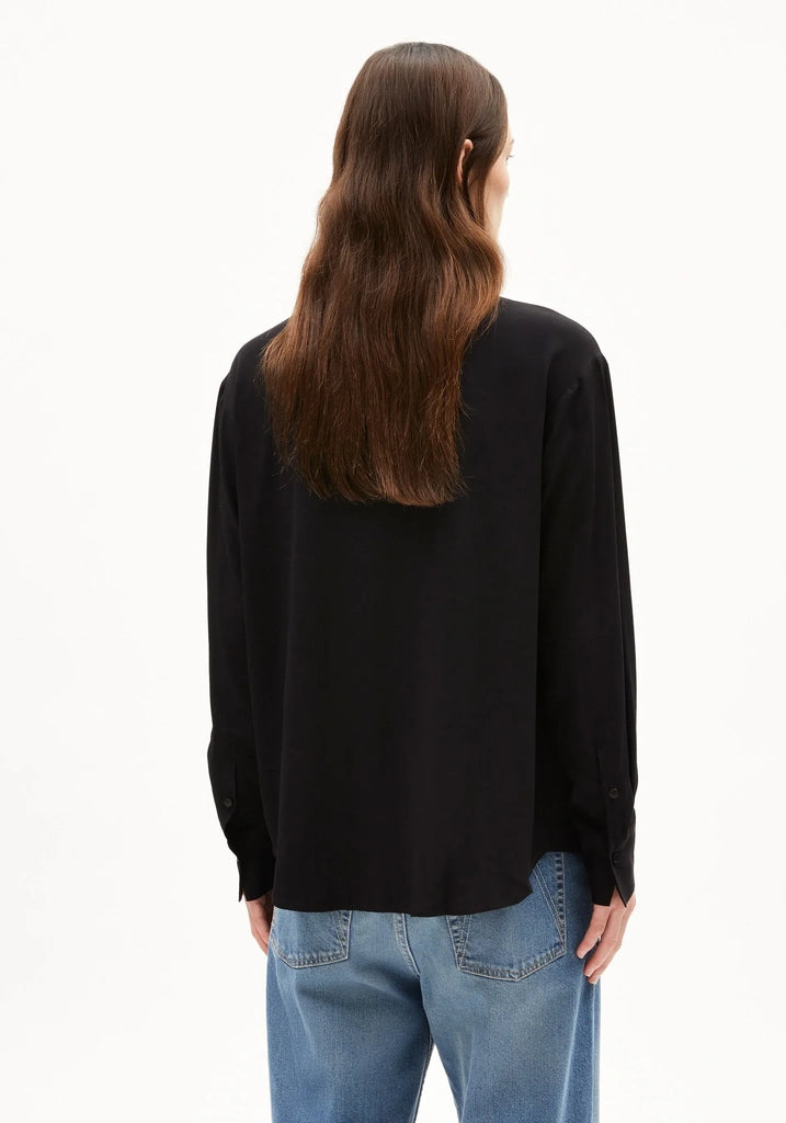 Back view of a woman wearing ARMEDANGELS Canada Larisaana Longsleeve Blouse in black, showing the relaxed fit and buttoned cuffs, against a white background.