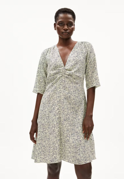 Woman wearing the ARMEDANGELS Canada Lilaat Waterdrop Dress in a seagreen and navy print, with a deep V-neck, gathered bust and short sleeves, against a white studio background.