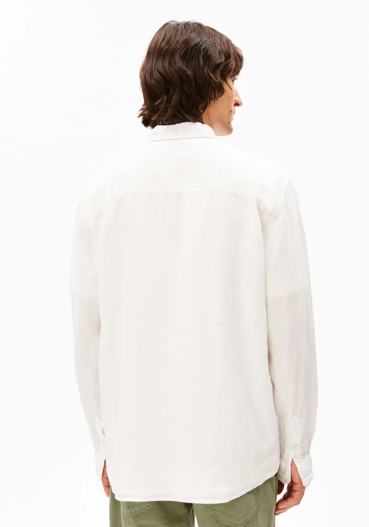 Back view of a man wearing the ARMEDANGELS Canada Linen Longsleeve Shirt in white with olive trousers on a white background.