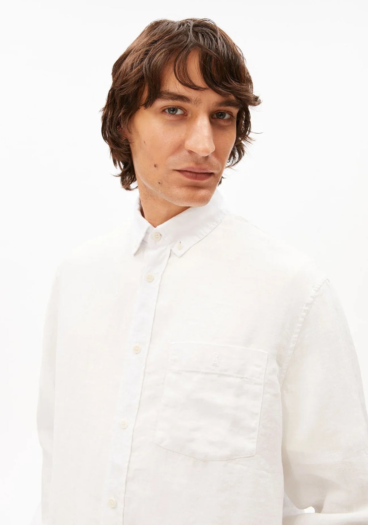 Close-up of the collar and chest pocket on the ARMEDANGELS Canada Linen Longsleeve Shirt in white, worn by a man.