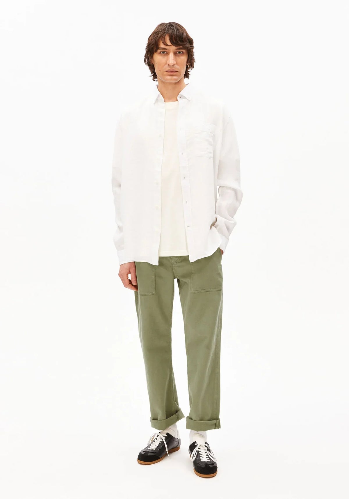 Full-length front view of a man wearing the ARMEDANGELS Canada Linen Longsleeve Shirt in white, worn open with olive trousers and black sneakers on a white background.