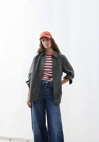 Person wearing a green shirt, red and white striped shirt, blue jeans, and a pink cap on a white background