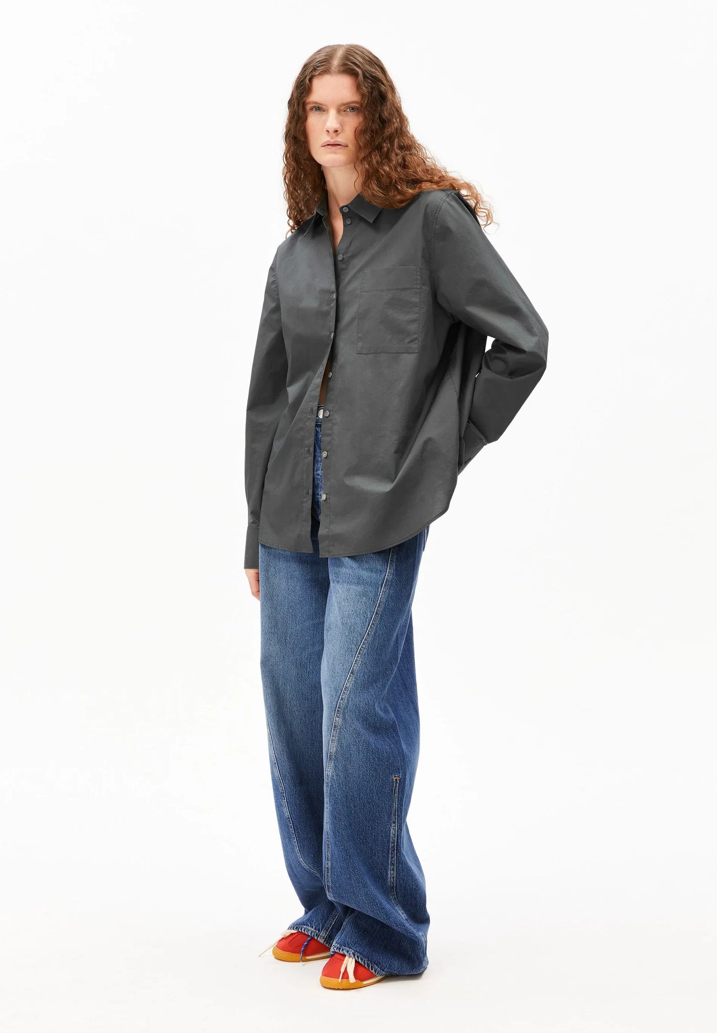 Person wearing a dark gray shirt and blue jeans on a white background
