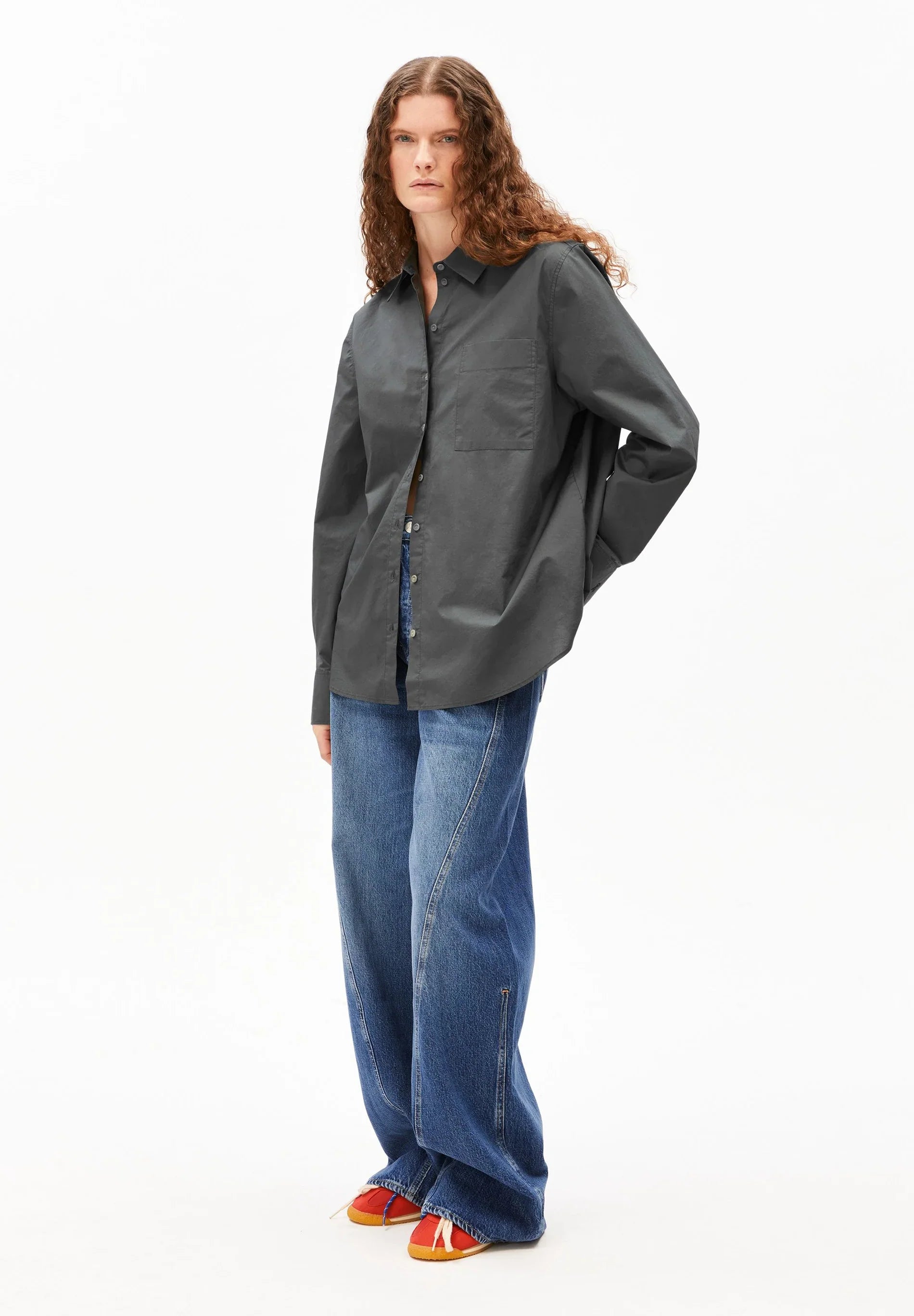 Person wearing a dark gray shirt and blue jeans on a white background