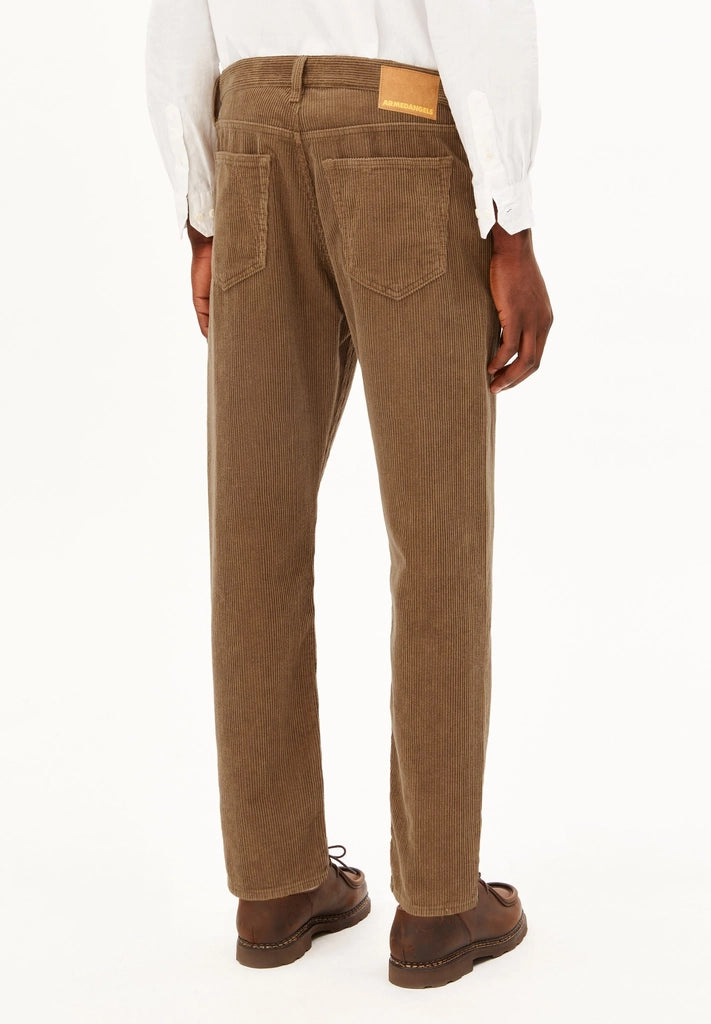 Back view of a man wearing ARMEDANGELS Canada Maakx Cord Trousers in Amberwood, showing the back pockets and waistband patch, against a white background.