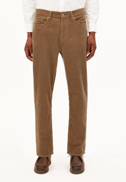 Front view of a man wearing ARMEDANGELS Canada Maakx Cord Trousers in Amberwood with a white shirt tucked in, against a white background.