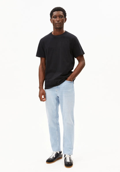 Full-length view of a man wearing the ARMEDANGELS Canada Maarkos Mid Weight T-Shirt in black with light-wash jeans and black sneakers on a white background.