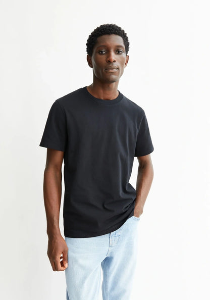 Man wearing a black t-shirt and light blue jeans against a white background