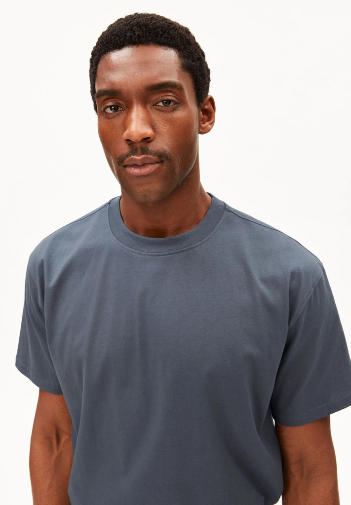 Close-up of the crew neckline and dropped shoulder on the ARMEDANGELS Canada Maarkos Mid Weight T-Shirt in moonshadow, worn by a man.