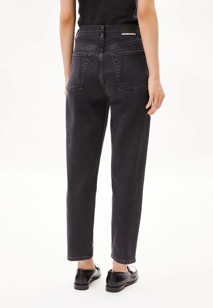 Back view of a woman wearing ARMEDANGELS Canada Mairaa mom jeans in black with loafers on a white background.