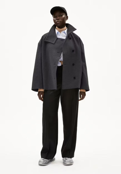 Full-length view of a woman wearing ARMEDANGELS Canada Majelaa wool coat in steel melange grey, open over a striped shirt with black trousers and silver sneakers.