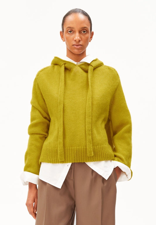 Woman wearing ARMEDANGELS Canada Mohair-Blend Knitted Hoodie in Mosslace over a white shirt with brown trousers, front view against a white background.