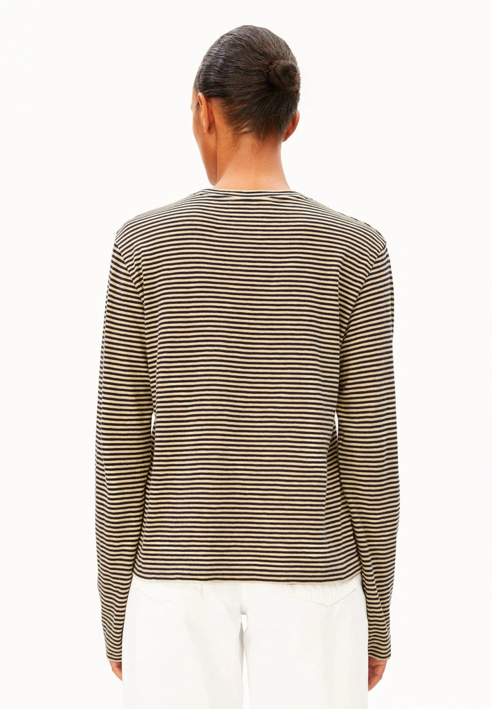 Back view of a woman wearing ARMEDANGELS Canada Slub Jersey Striped Longsleeve Shirt in Tinted Navy-Golden Hay with white jeans, against a white background.