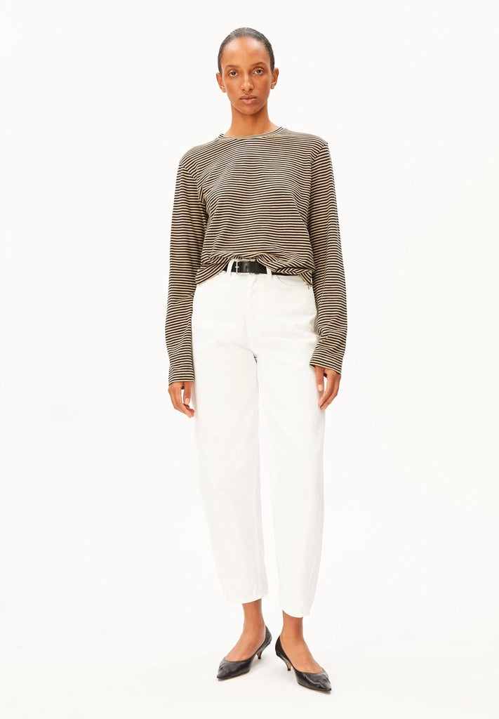 Full-length front view of a woman wearing ARMEDANGELS Canada Slub Jersey Striped Longsleeve Shirt in Tinted Navy-Golden Hay, tucked into belted white jeans with black heels, against a white background.