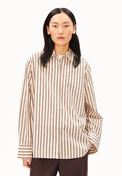Woman wearing ARMEDANGELS Canada Striped Wide Blouse in Oatmilk-Claystone with dark brown trousers, front view against a white background.